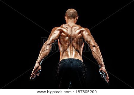 The back view of torso of attractive male body builder on black background.