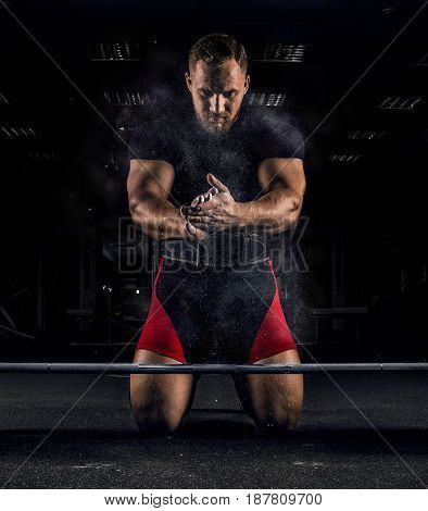 Ahlete Kneels In The Gym And Claps His Hands After Which The Dust From The Chalk Flies