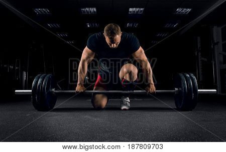 Athlete Is Standing On His Knee And Near The Bar And Is Preparing To Make A Deadlift