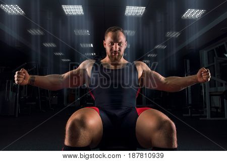 The Weightlifter Sits On A Bench With Arms Outstretched