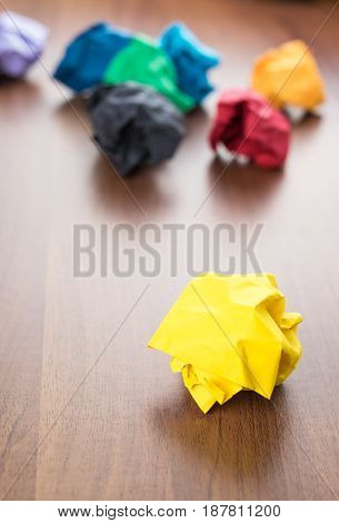 Yellow Crumpled Paper Ball On Dark Brown Wood Table With Group Of Colorful Crumpled Paper Ball At Ba