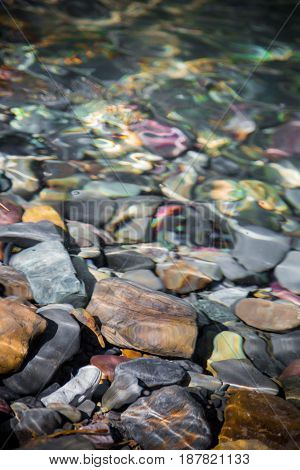 Closeup of rocks of different colors and sizes stacked along the riverside