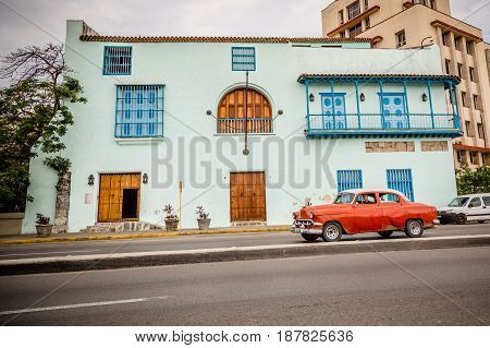 Old red American car driving urban Cuban capital city