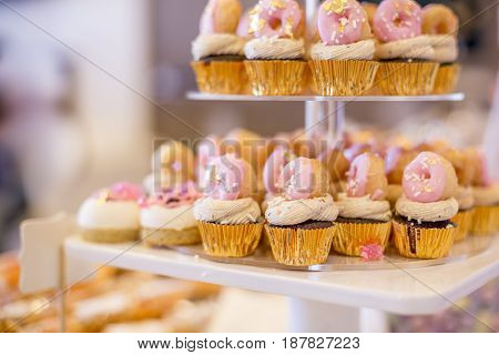Mini Chocolate Cupcakes Topped With Mini Pink Donuts On A Dessert Table.