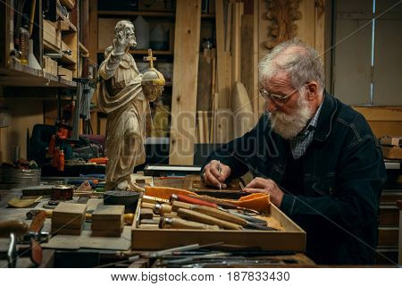 Senior wood carving professional during work