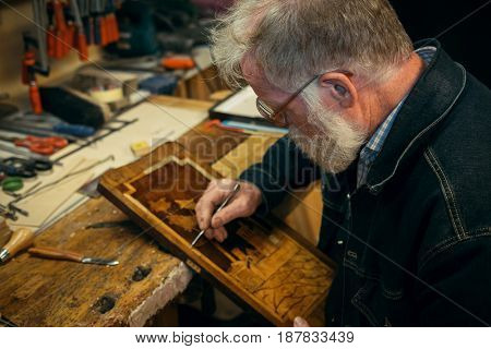 Senior wood carving professional during work