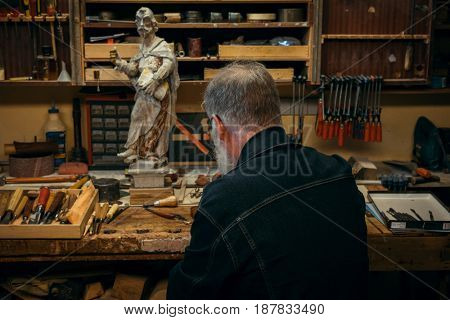 Senior wood carving professional during work