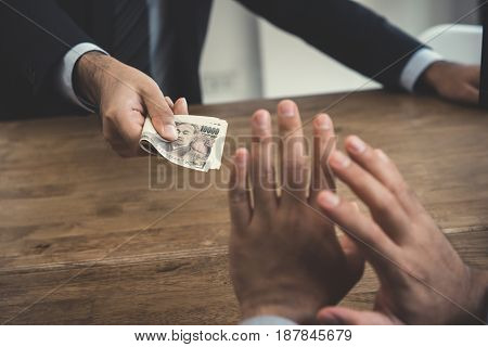 A man refusing money Japanese yen from a busisnessman - anti bribery and corruption concepts