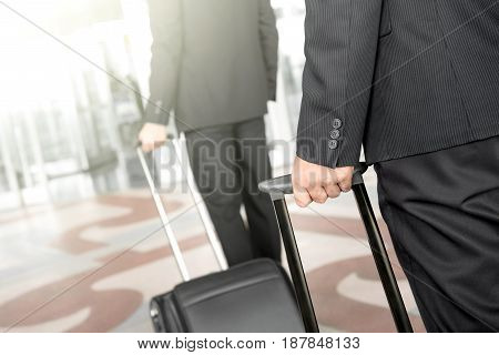 Businessmen pulling baggage while walking at the airport - business travel concept