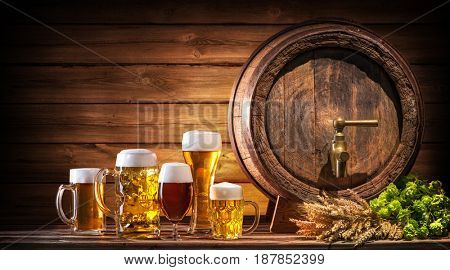 Oktoberfest beer barrel and beer glasses with wheat and hops on wooden table