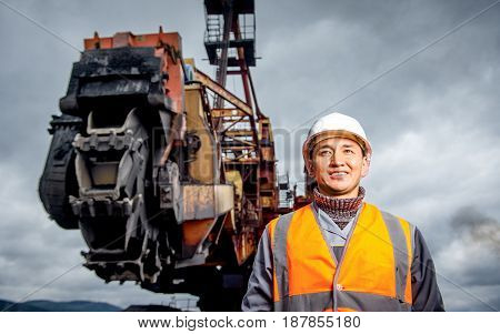 coal mining worker with rotary excavator on the background