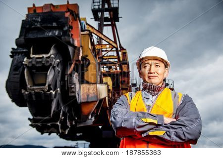 coal mining worker with rotary excavator on the background