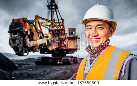 coal mining worker with rotary excavator on the background