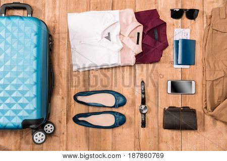 Flay lay of business holiday concept with clothes digital gadgets passport and tickets on wooden floor.