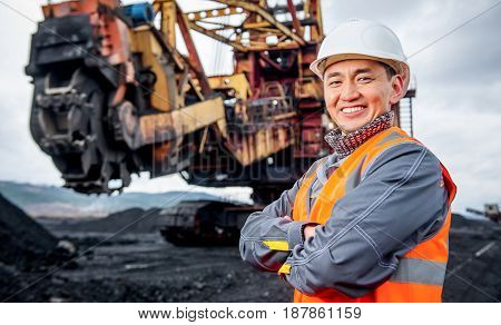 coal mining worker with rotary excavator on the background