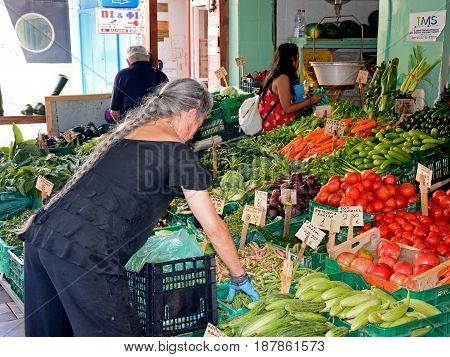 HERAKLION, CRETE - SEPTEMBER 19, 2016 - Cretan stallholder sorting vegetables on a market stall in the city centre Heraklion Crete Greece Europe, September 19, 2016.