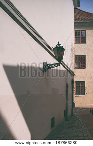 Street lamp on wall with long shadow from the house with Windows on a Sunny spring day