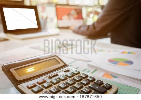 Close up of calculator and business man working document and laptop in office morning light. business concept.