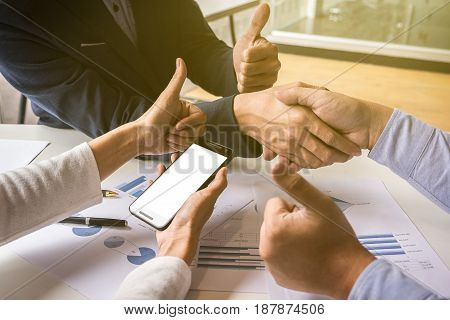 Teamwork process Close-up of two business people shaking hands while sitting at the working place.