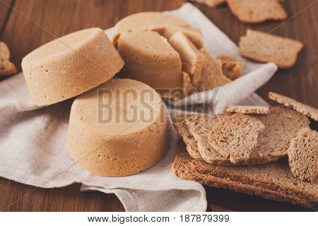 Norwegian homemade brown cheese brunost with crackers or crispbread on wooden desk, close-up, selective focus