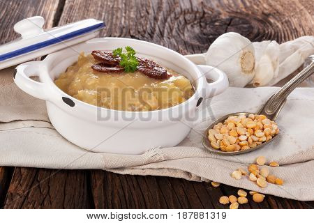 Lentil soup on wooden table with sausage.