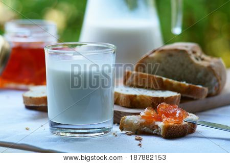 A glass of milk with bread and homemade jam