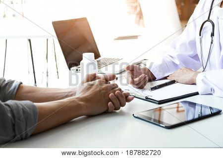 Healthcare and Medical concept patient listening intently to a female doctor explaining patient symptoms or asking a question as they discuss paperwork together in a consultation.