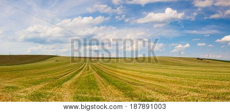 Tractor on the harvested empty field on the hills at sunset.Panorama picture.