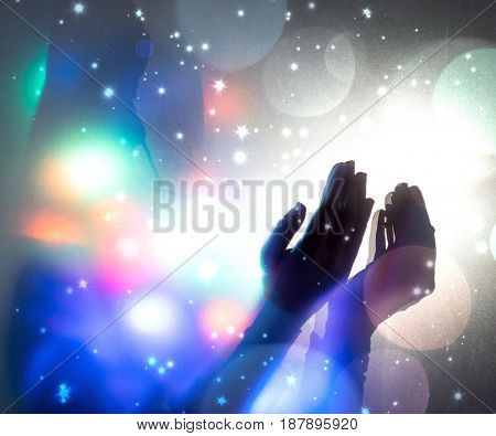 Hands praying in dark room with nice lights around her