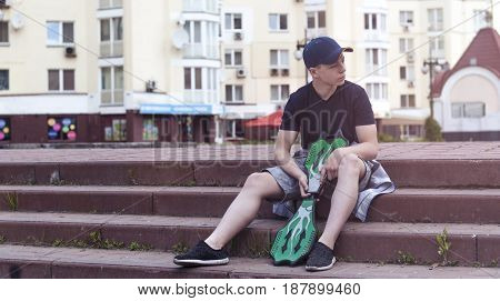 Young man with a skateboard on the street of a big city