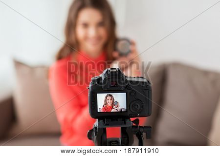 blogging, technology, videoblog, makeup and people concept - happy smiling woman or beauty blogger with bronzer, brush and camera recording tutorial video at home
