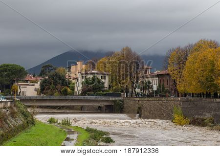 The view of a bridge and embankment of Bisenzio River in a cloudy day. Prato. Tuscany. Italy.