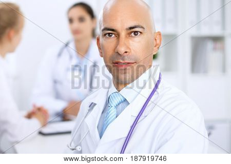 Confident bald doctor man with medical staff at the hospital.