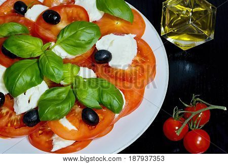 Caprese salad. Classic caprese salad. Italian traditional caprese salad ingredients. Mediterranean food. Caprese salad Tomato and mozzarella with basil leaves on wooden background.