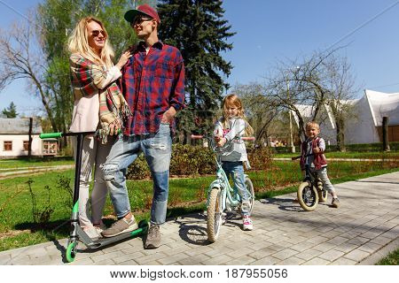 Young family with children on scooters in park during day