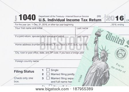 A US Federal tax 1040 income tax form with money and refund check