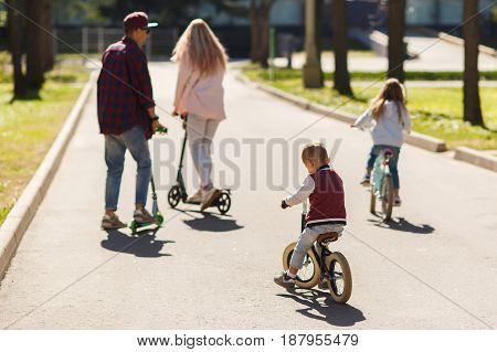 Family with children in active walk on scooters at park