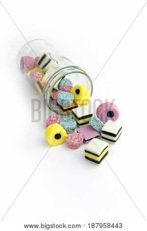 Small glass jar with colored jelly chewing sweets on the white background