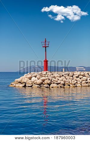 Beautiful seascape with lighthouse. Calm sea and a lighthouse on the pier. Red white solitary pulp