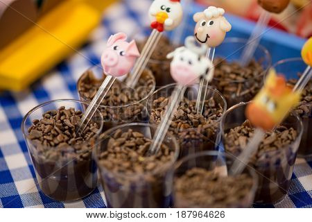 Brigadeiro (brazillian mix of chocolate and condensed milk) with animals decoration spoon in a small plastic glass