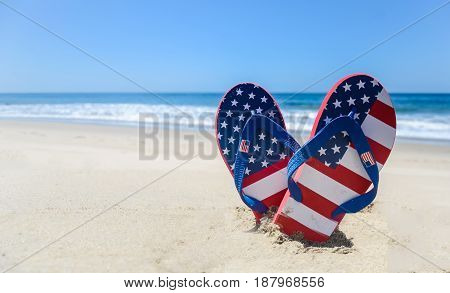 Patriotic USA background with flip flops and decorations on the sandy beach