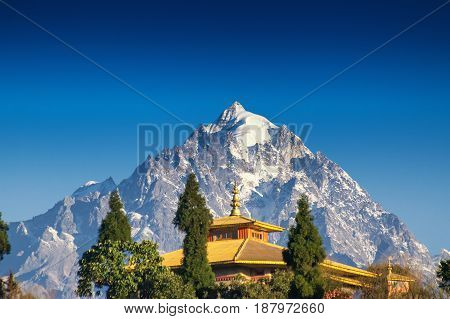 Mount Pandim 6691 mtrs 21952 feet high one of the highest peaks of Himalayan Mountain range - with top of Rinchenpong Monastery in foreground clear blue sky above. Rinchenpong Sikkim India