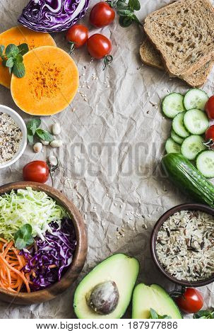 Healthy vegetarian food set background with free space for text. Cabbage avocado tomatoes cucumbers pumpkin wild rice on a paper background top view. Flat lay
