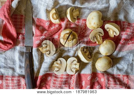 Close up fresh mushrooms cut in halves and old knife lying on cloth for abstract background