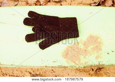 Lost Woolen Gloves On Green Bench. Sandy Gren Wooden Bench.  Sandbox With Dirty Sand In Kindergarden