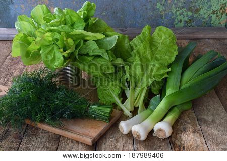 Composition Of Green Herbs And Vegetables. Organic Spring Mix For Salad On Brown Wooden Background.