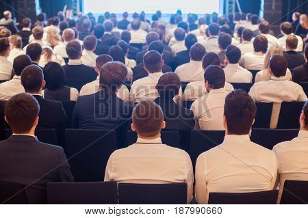 Audience at the conference hall. Speaker giving a talk in conference hall at business event. Business and Entrepreneurship concept. Lens focus on people in audience from rear.