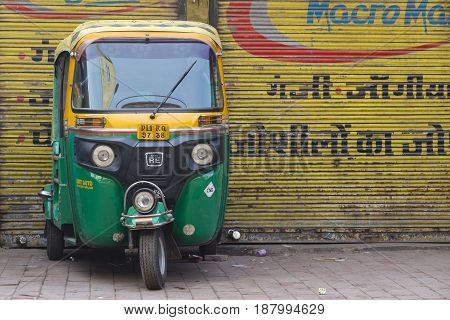 NEW DELHI INDIA - JANUARY 24 2017 : Auto rickshaw taxis on a road in New Delhi India. These iconic taxis have recently been fitted with CNG powered engines in an effort to reduce pollution