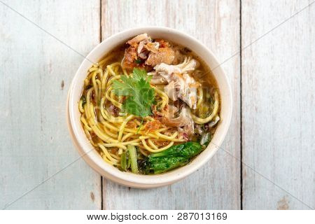 Asian soup noodles and chicken in bowl on wooden background. Top view flat lay.