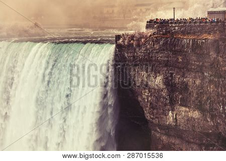 View Of Niagara Falls From Canada, Day Time. Some People Overlook A Balcony Right Next To The Waterf